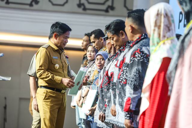 Penjabat (Pj) Gubernur Sumatera Utara (Sumut) Hassanudin menyerahkan sertifikat tanah secara simbolis pada masyarakat di Aula Raja Inal Siregar, Kantor Gubernur Sumut, Jalan Pangeran Diponegoro Nomor 30, Medan, Senin (4/12/2023). Foto/Diskominfo Sumut